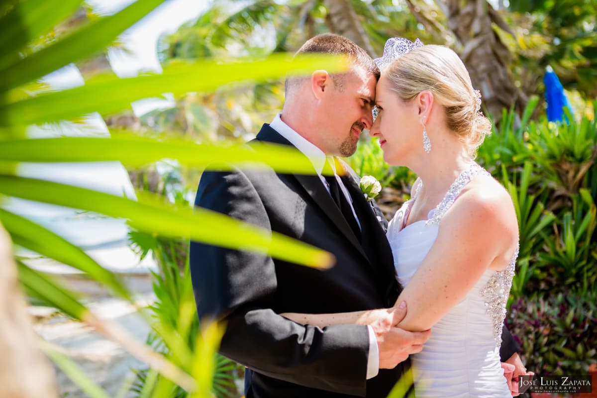 A couple embraces tenderly in a tropical setting during their wedding ceremony.