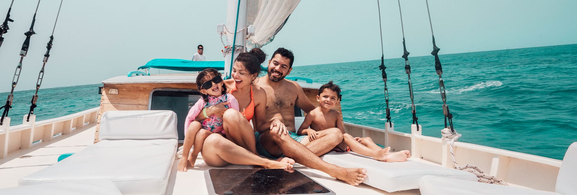 A family enjoys a sunny day on a sailboat in the ocean.
