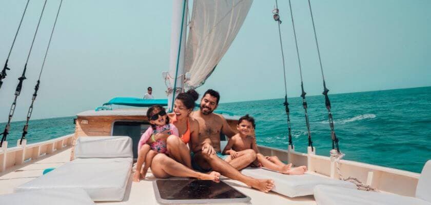 A family enjoys time together on a sailboat, smiling and relaxing by the ocean.