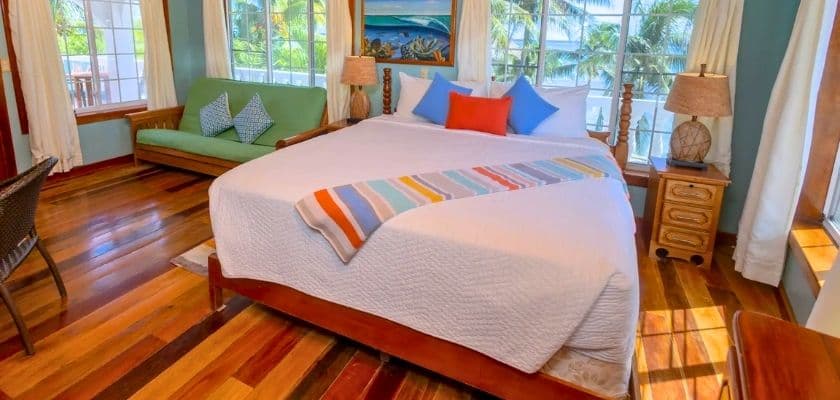 Bright and inviting bedroom featuring a large bed, colorful decorative pillows, and a cozy seating area by the windows.