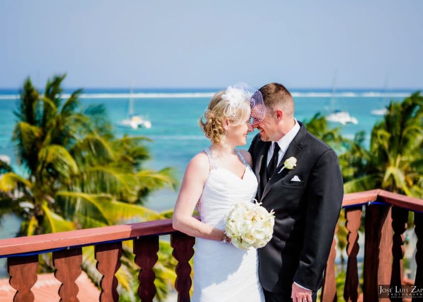 A bride and groom share a romantic moment on a balcony overlooking a tropical seascape. A bride and groom share a romantic moment on a balcony overlooking a tropical seascape.