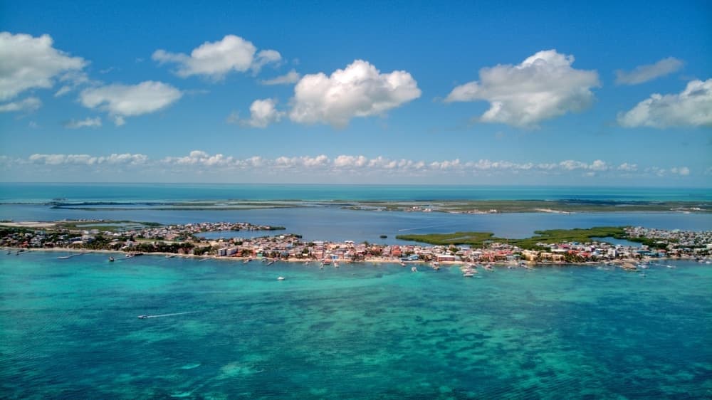 Aerial view of a vibrant coastal town surrounded by clear turquoise waters and lush green vegetation.