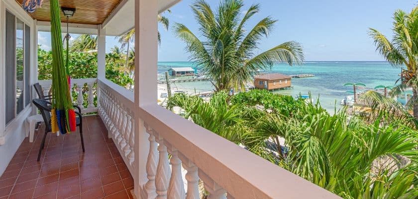 A serene balcony view overlooking turquoise waters and lush palm trees.
