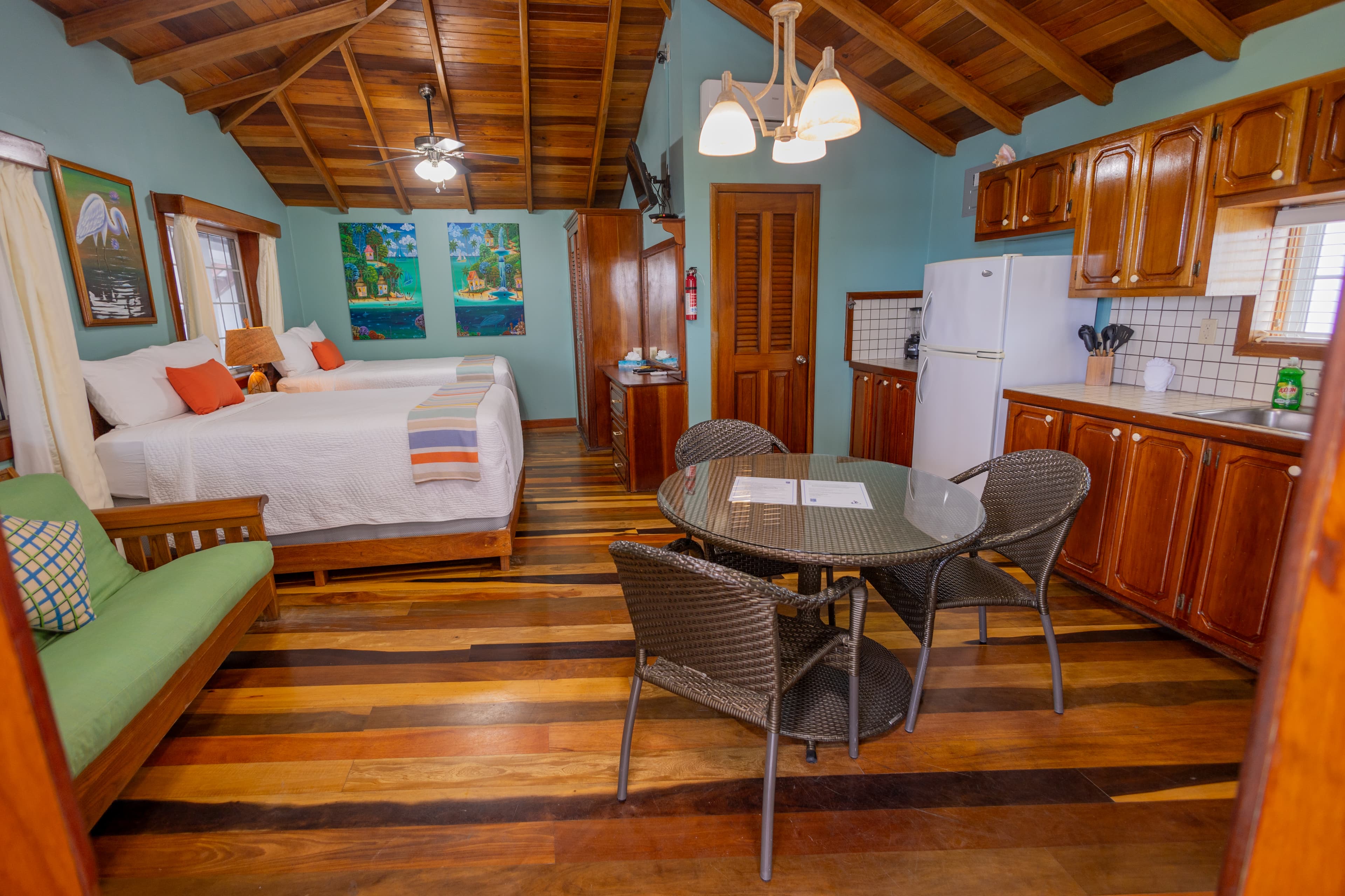 A cozy cabin interior featuring a kitchen, two beds, and a dining area with wooden accents.