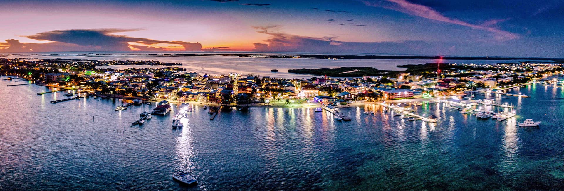 Aerial view of a vibrant seaside town illuminated at dusk.