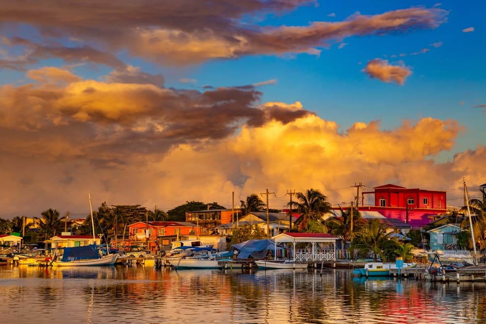 Sunset over a colorful waterfront village with boats reflected in the calm water. Sunset over a colorful waterfront village with boats reflected in the calm water.