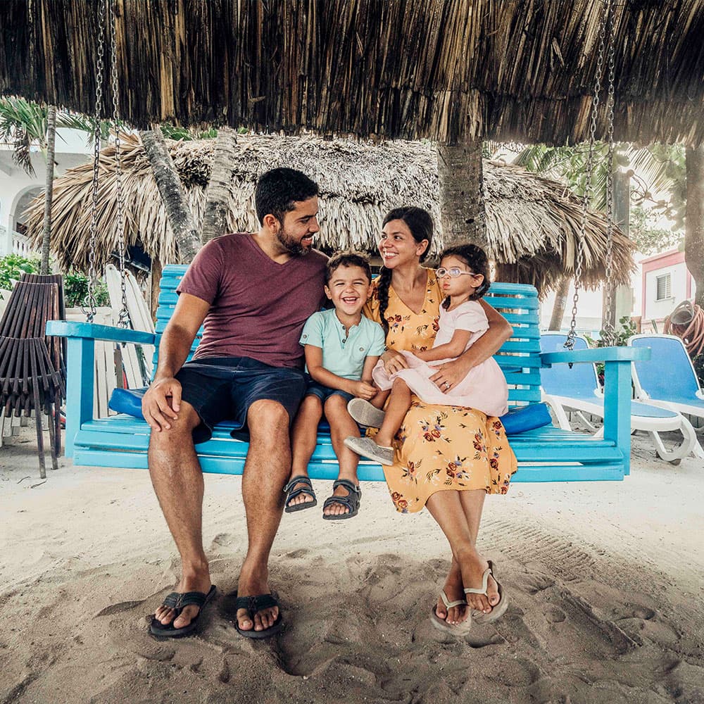 A family of four enjoys a joyful moment on a swing at the beach.