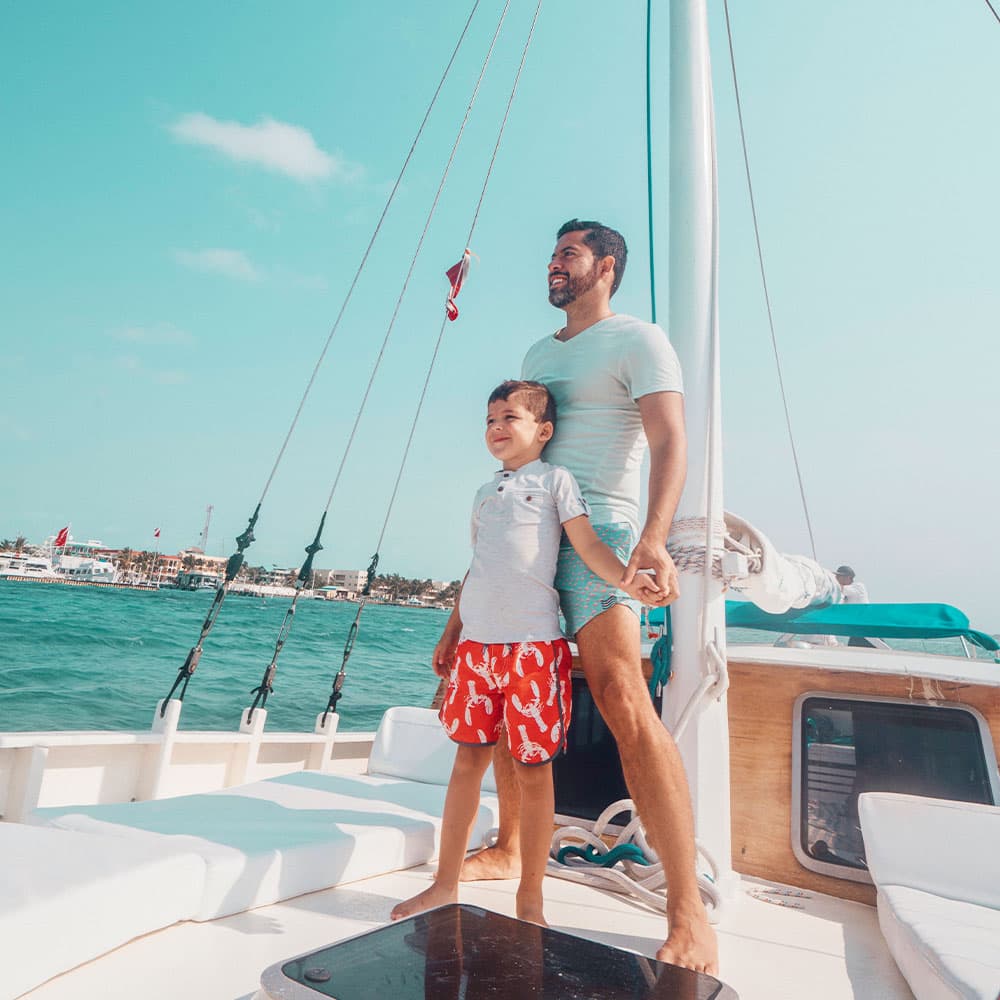 A man and a boy stand together on a boat, enjoying the sea view.