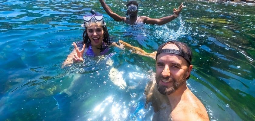 Three friends taking a selfie while snorkeling in crystal clear waters.