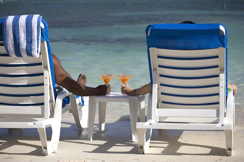 Couple enjoying drinks on the beach in front of one of the best Belize resorts for adults